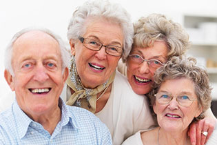 Smiling senior woman with new dental implants sitting in the dental office and looking at the mirror